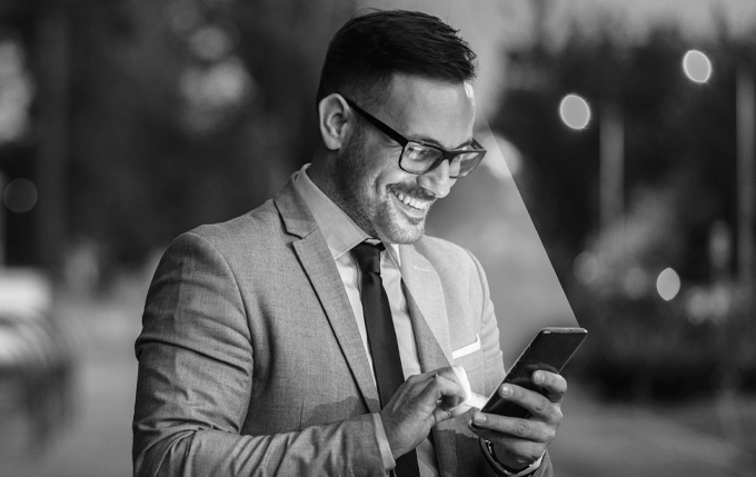 image of male holding phone getting face scanned. Image is in black and white