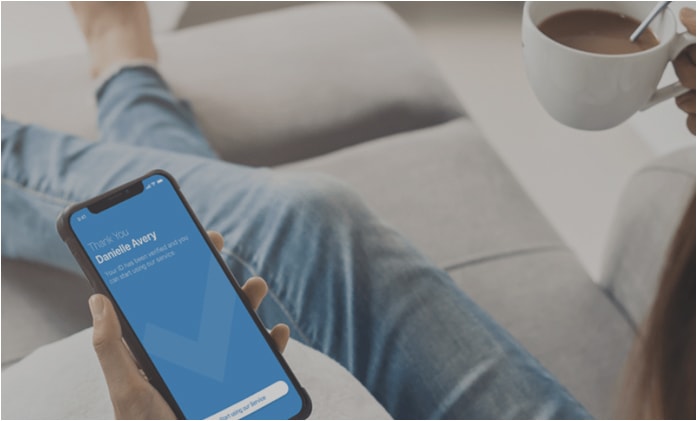 image of female sitting on couch with smart phone in left hand and a cup of coffee in her right hand. Phone screen reads: Thank you Danielle Avery.