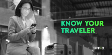 image of women sitting down with her legs crossed looking at her smart device. The women is wearing glasses with a suitcase next to her. Text on image reads: Know Your Traveler.